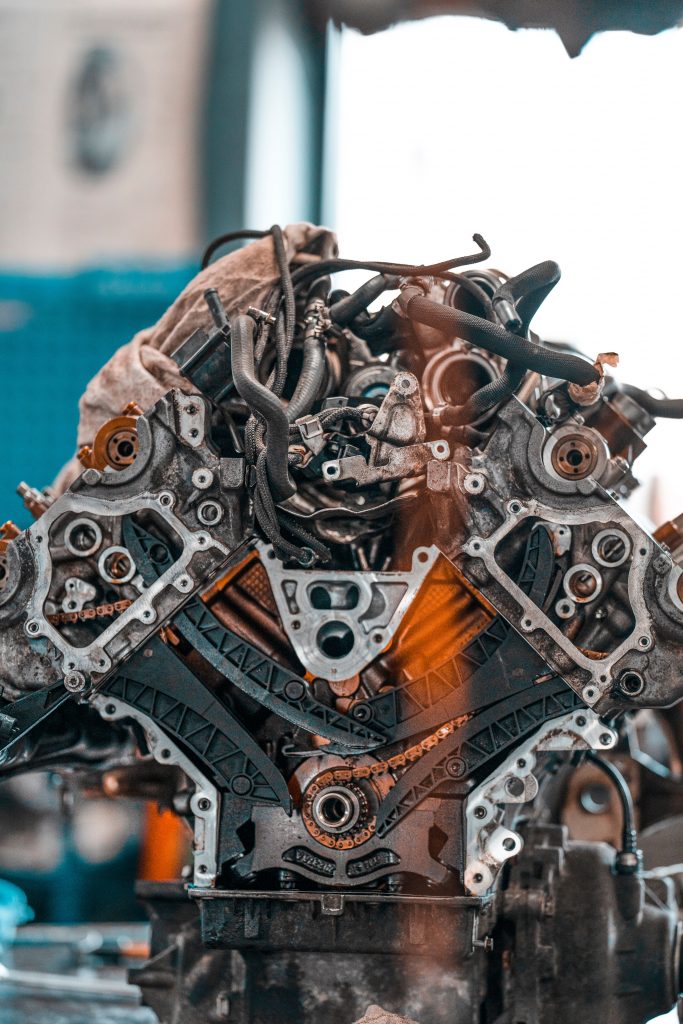 Car engine with various metal details placed on workbench in modern repair service